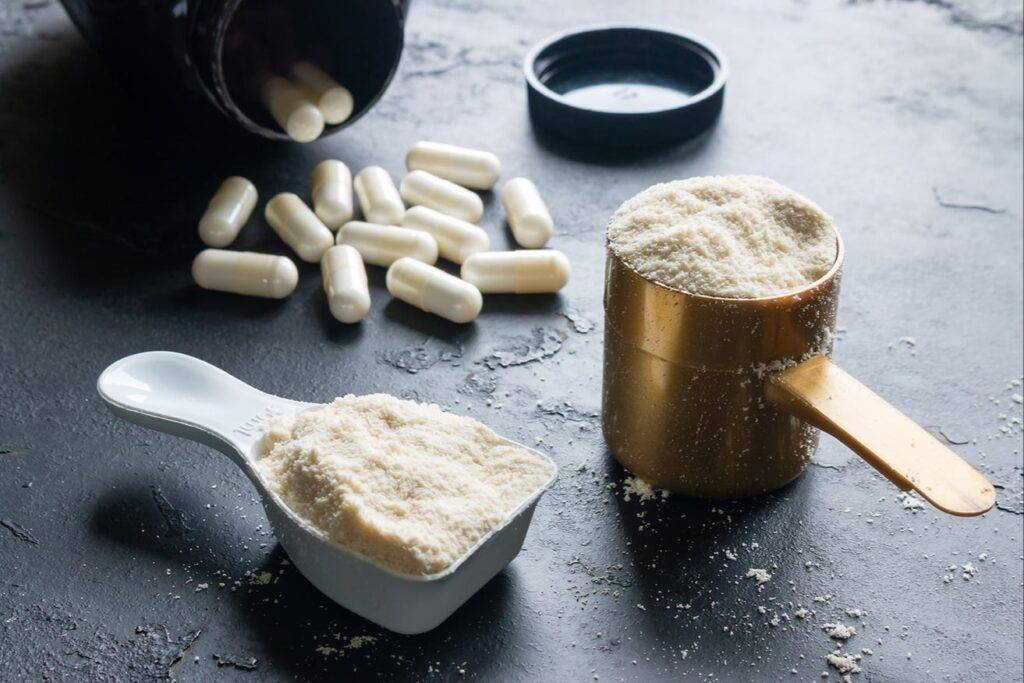 Image of powder in scoops and pills falling out from a bottle.