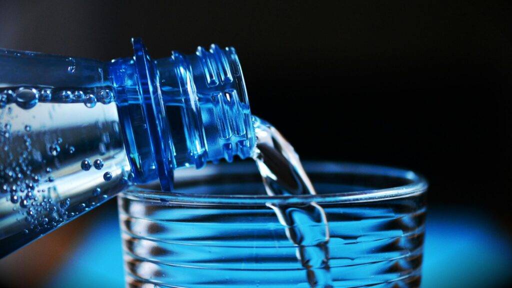 Close-up of Bottle Pouring Water on Glass.